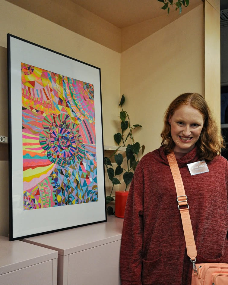 A visitor smiling beside a colourful painting