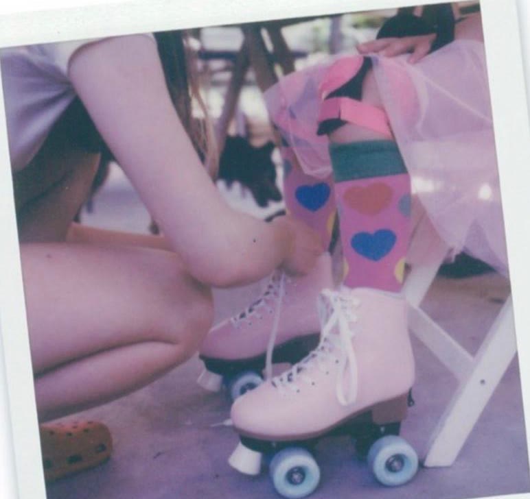 Polaroid photograph of someone lacing pink roller skates