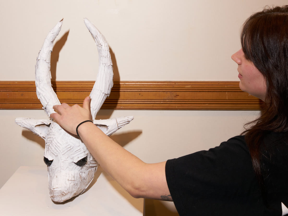 A visitor touching a white sculpted bull's head