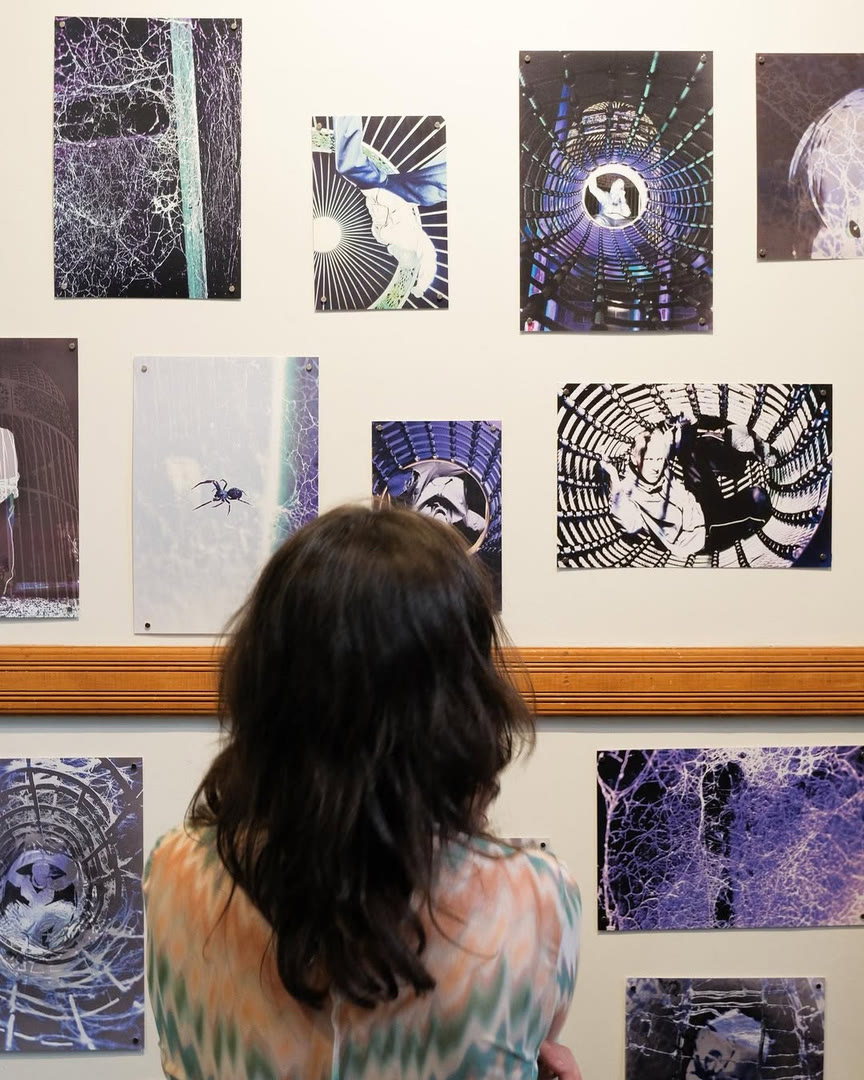 A visitor looking at a wall of black and white prints